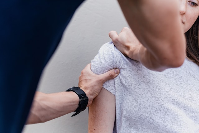 An osteopath assessing a person's shoulder